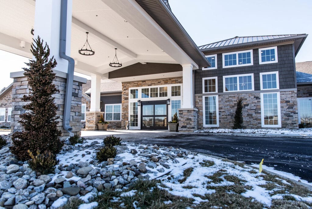 Covered entryway with stone columns and winter landscaping at Charter Senior Living of White House, TN.
